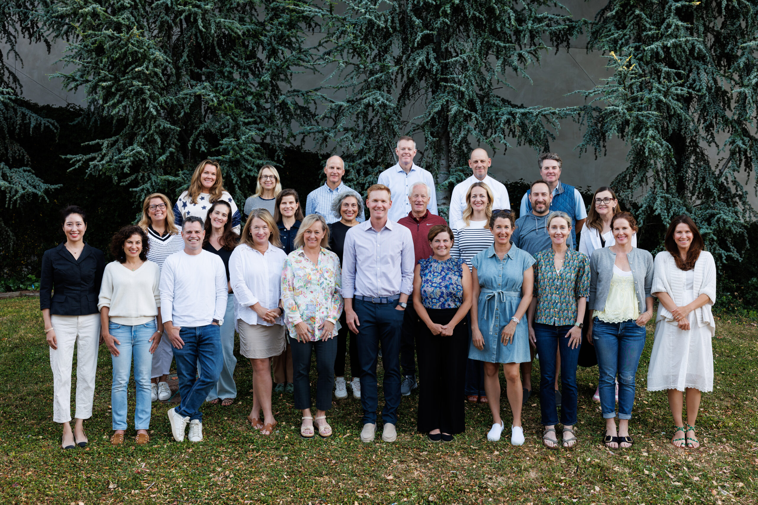 A large group of about 30 board members smiles, standing in the grass
